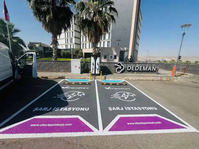 Dedeman Hotel otoparkında Checkpoint marka çizgileriyle ayrılmış iki şarj yeri ve DC şarj ünitesi