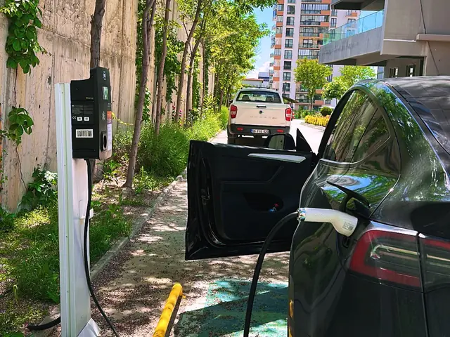 Bir konut sitesinin bahçesinde direğe monte AC şarj cihazına bağlı elektrikli otomobil