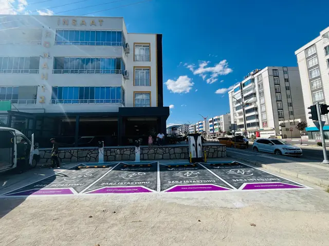 Cadde üstündeki bir binanın önünde dört şarj yeri ve DC şarj ünitesi