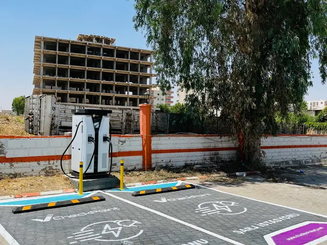 Ağaçların gölgesinde DC şarj ünitesi ve marka çizgili şarj yerleri